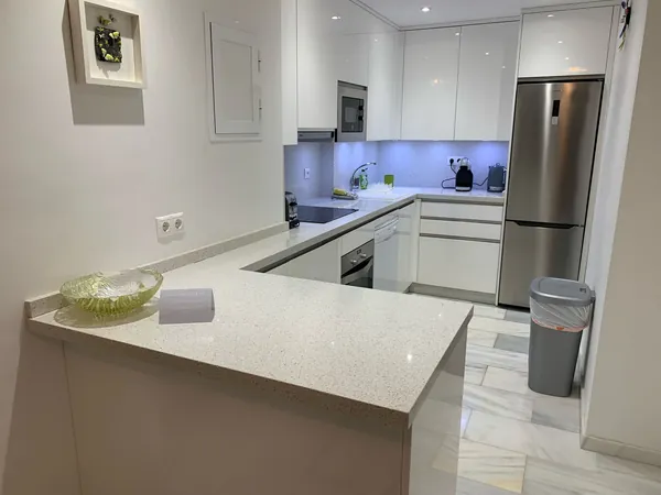 A spotless white kitchen with a breakfast bar after the morning reset