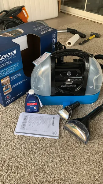 A carpet spot cleaning machine and its attachments ready for a stain